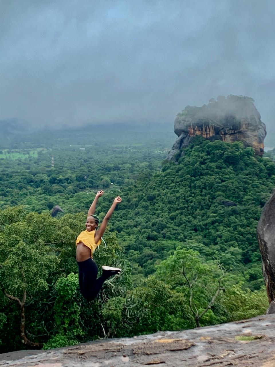 Reisende blickt bei Sonnenaufgang vom Pidurangala auf den Felsen von Sigiriya, Sri Lanka